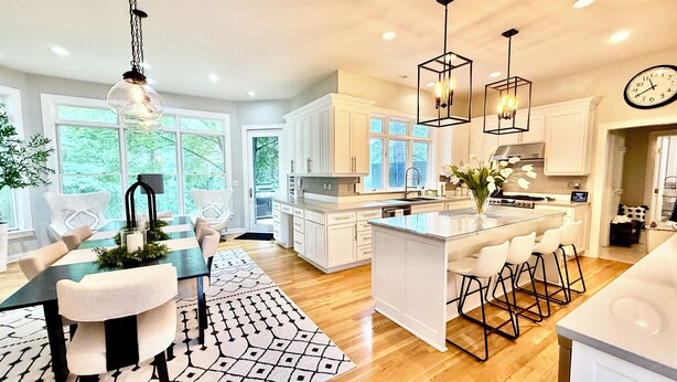 A modern kitchen with white cabinetry, a central island with bar stools, pendant lighting, and a large window providing natural light. - EXQUISITE, DESIGNER HOME, 4BD/2.5BA, 4 miles from MAYO CLINIC (Rochester)