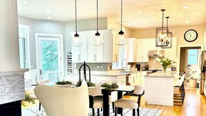 A spacious kitchen with white cabinets, a dining area with a black and white rug, and a large clock on the wall. - EXQUISITE, DESIGNER HOME, 4BD/2.5BA, 4 miles from MAYO CLINIC (Rochester)