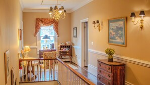 A staircase with a wooden railing leading to an upper floor, a chandelier, and a wall-mounted lamp.
