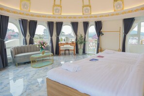 A hotel room with a large bed, a sofa, a desk, and a view of the city. - Hamia Villa DaLat (Xuan Truong - Da Lat)