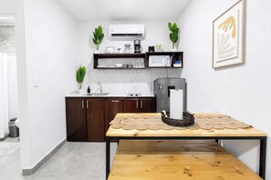 A modern kitchen with dark wooden cabinets, white countertops, a microwave, and an air conditioner. - The Fern Studio: Cozy & Modern for Nature Lovers (Jaco)