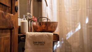 A bathroom with a wooden door, a towel hanging on a rack, a copper basin, and a mirror. - San Ignacio Estancia Andina (Guaymallen)