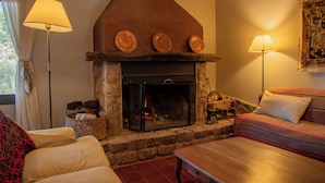 A cozy living room with a stone fireplace, a wooden table, and a sofa. - San Ignacio Estancia Andina (Guaymallen)