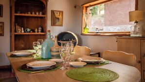 A dining table set with plates, glasses, and a pitcher, surrounded by chairs and a wooden cabinet. - San Ignacio Estancia Andina (Guaymallen)