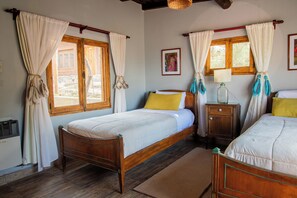 A bedroom with two wooden beds, a nightstand, a lamp, and a window with curtains. - San Ignacio Estancia Andina (Guaymallen)