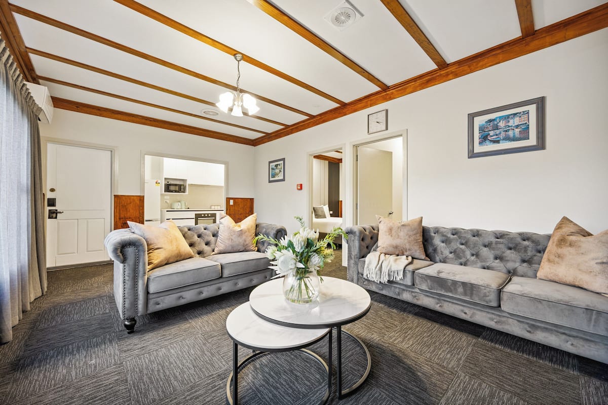 A modern living room with a grey sofa set, a round coffee table, and a chandelier.