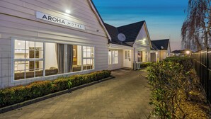 A row of Aroha Motel buildings with large windows and a paved walkway. - Aroha Motel (Auckland)