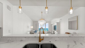 Una cocina moderna con un lavamanos doble, encimeras de mármol e iluminación colgante.