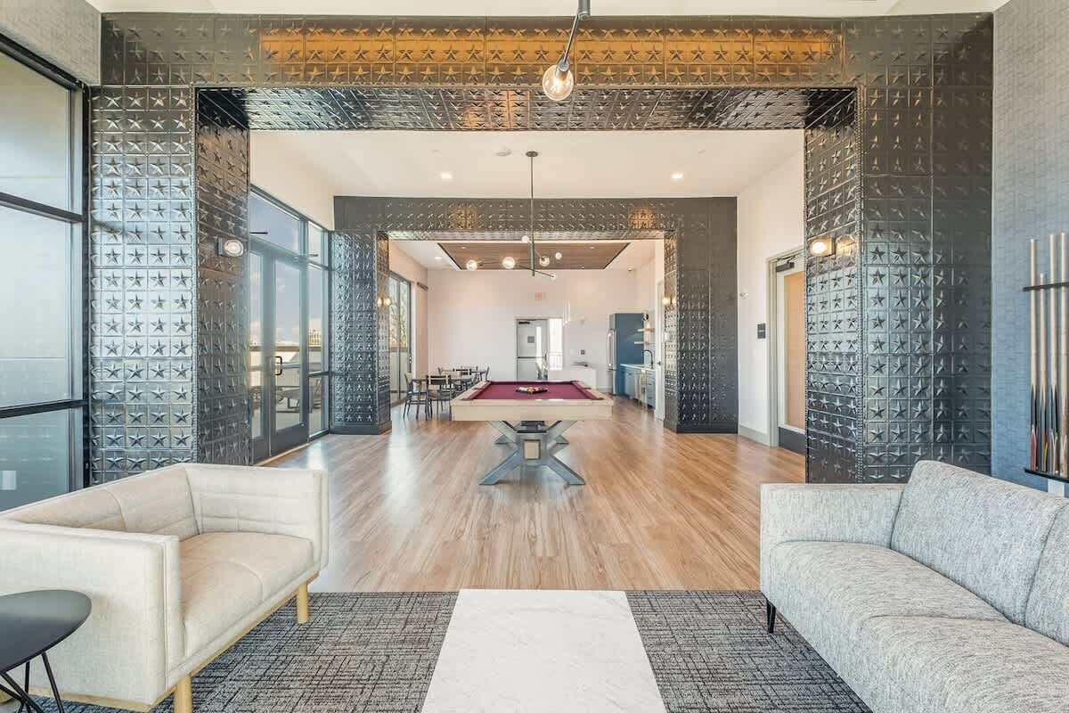 A spacious living area with a pool table, two sofas, and a dining area.