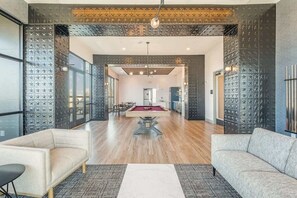 A spacious living area with a pool table, two sofas, and a dining area.