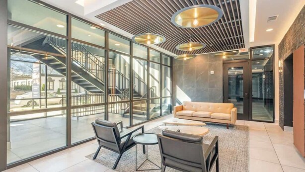 Un hall d’entrée moderne avec un escalier, des murs en verre, un canapé et une table basse.