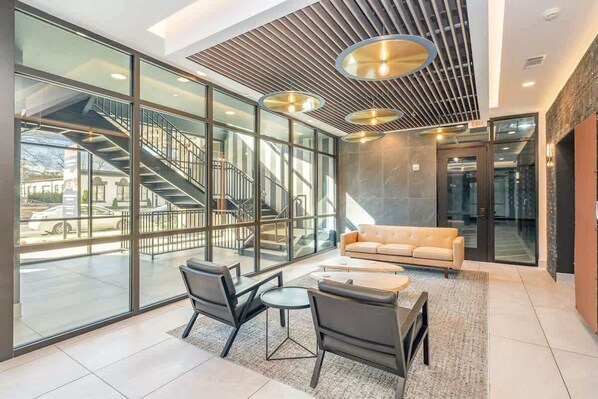 A modern lobby with a staircase, glass walls, a sofa, and a coffee table.