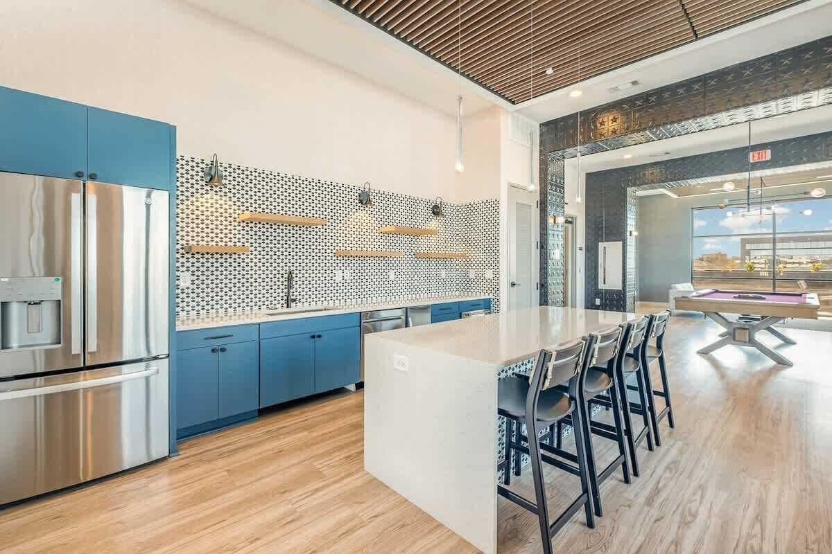 Et moderne køkken med rustfrie apparater, et mønstret backsplash og en central ø med barstole.