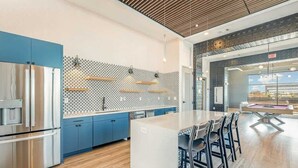 Une cuisine moderne dotée d’appareils électroménagers en acier inoxydable, d’un crédence décorée et d’un îlot central agrémenté de tabourets de bar.