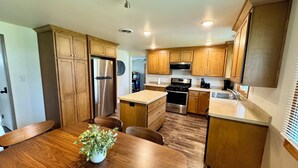 Une cuisine moderne dotée de meubles en bois, d’appareils électroménagers en acier inoxydable et d’un îlot central avec des sièges.