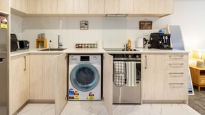 A compact kitchen with a washing machine, a coffee maker, and a sink.