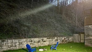 Ein Garten mit einer Steinmauer, zwei blauen Stühlen und einer Holzterrasse.