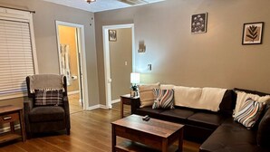 Ein Wohnzimmer mit Sofa, Sessel, Couchtisch und Lampe.