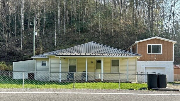 Ein eingeschossiges Gebäude mit Satteldach, einer Veranda und einer Garage.