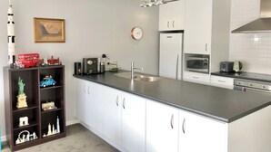 Een moderne keuken met witte kastjes, een roestvrijstalen koelkast, een magnetron en een koffiezetapparaat op het aanrecht.