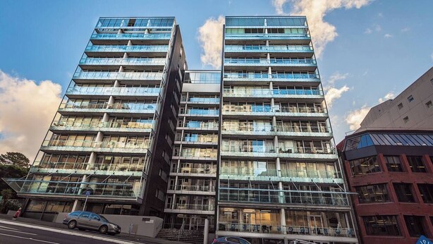 Een modern hoog gebouw met meerdere balkons en grote ramen.