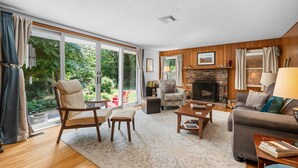 A spacious living room with a fireplace, large windows, and a cozy seating area.