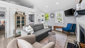 A modern living room with a grey sofa, a blue armchair, and a wooden cabinet. - Beachside Bliss at Sunset Retreat (West Dennis)