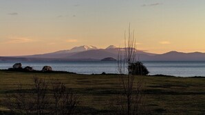 A landscape with a mountain range, a body of water, and a grassy field.