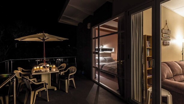 An outdoor dining area with a table and chairs, a large umbrella, and candles.