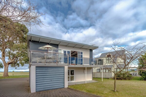 A modern two-story house with a garage, a balcony with outdoor furniture, and a view of the sea. - Lakeside Delight with Mountain Views (Taupō)