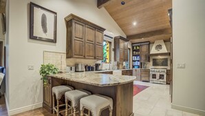 A spacious kitchen with wooden cabinets, a marble island with bar stools, and a large oven. - Broadmoor Bliss (Colorado Springs)