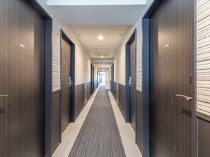 A modern hotel hallway with dark wood paneling, a carpeted floor, and doors with room numbers. - Hotel Excellence Enmachi Ekimae (Kyoto)