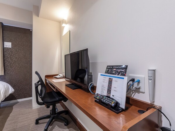 A hotel room with a wooden desk, a black office chair, a flat-screen monitor, a control panel, and a bed with a white comforter. - Hotel Excellence Enmachi Ekimae (Kyoto)