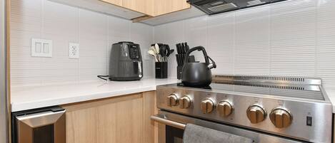 Een praktische keuken met een roestvrijstalen fornuis, een magnetron en een koffiezetapparaat.