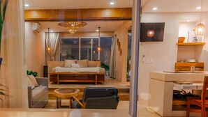 A modern living room with a sofa, a dining table, and a kitchen area.