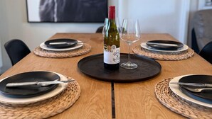A dining table set with plates, cutlery, and a bottle of wine, with a framed picture of a bull on the wall behind. - Southern Comfort Twizel Escape (Twizel)