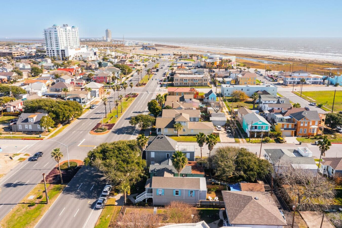 A residential area with houses, streets, and a beach in the background.
