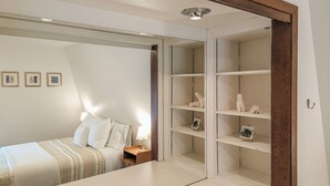 Ein Schlafzimmer mit einem Bett, Nachttischen, einem Spiegel und einem Regal.