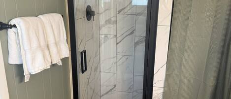 A bathroom with a glass-enclosed shower, a toilet, and a sink.