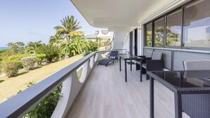 Ein Balkon mit Meerblick, ausgestattet mit Tisch und Stühlen, umgeben von Grünpflanzen.