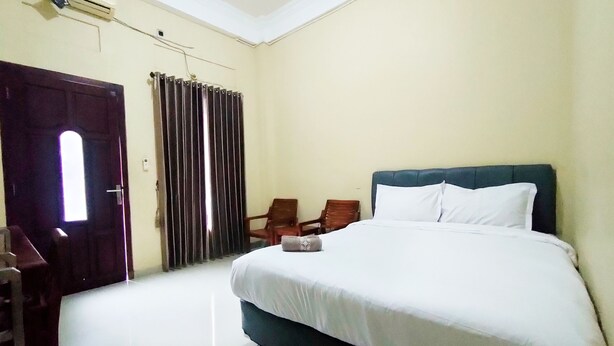 A hotel room with a bed, a chair, a desk, and a window with curtains. - Omah Sewu 68 By Reccoma (Surabaya)