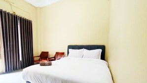 A hotel room with a large bed, two wooden chairs, and a window with curtains. - Omah Sewu 68 By Reccoma (Surabaya)
