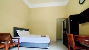 A room with a bed, two wooden chairs, a desk, and a wardrobe. - Omah Sewu 68 By Reccoma (Surabaya)