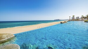 Ein klares, blaues Schwimmbecken mit Sandstrand und blauem Himmel.