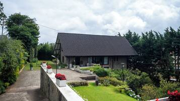 A modern house with a sloped roof, surrounded by a well-maintained garden with various plants and flowers.