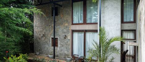 Una casa de piedra con techo de tejas, ventanas amplias y un patio con mobiliario exterior.