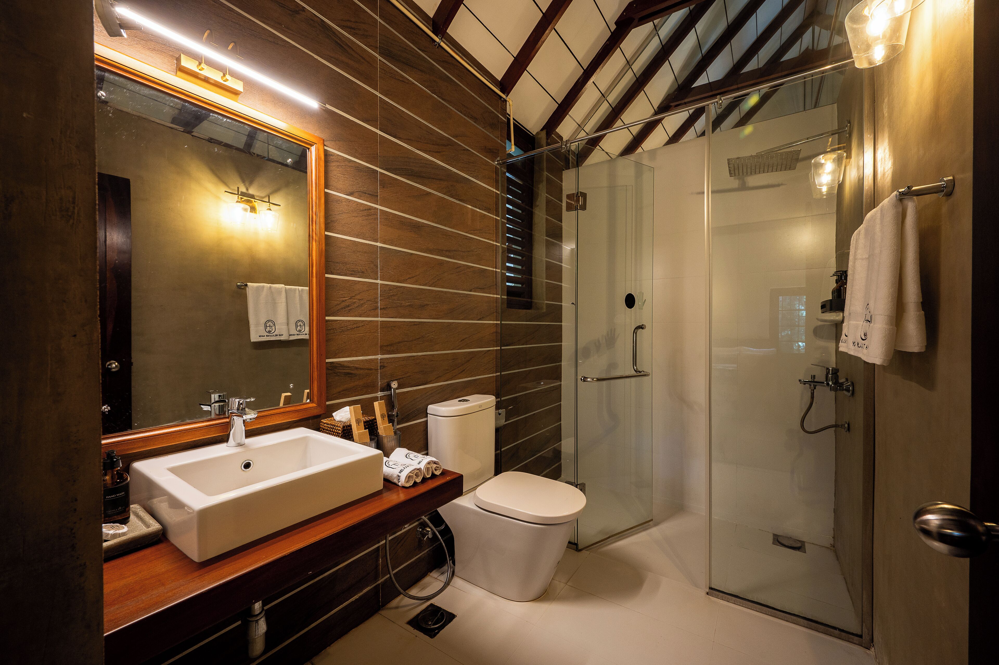 A modern bathroom with a large mirror, a sink, a toilet, and a glass-enclosed shower.