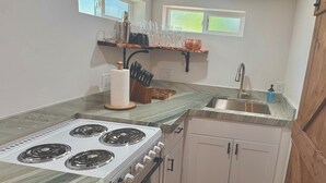 A kitchen with a gas stove, a sink, and a window above the counter. - Outlaw Hideaway Downtown (Prescott)