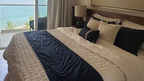 A hotel room with a large bed, a view of the sea, and a balcony. - Beachfront Studio with Balcony, Rooftop Pool & Gym Access (Puerto Vallarta)