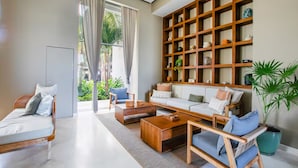 A modern living room with a sofa set, coffee table, and a wooden bookshelf. - Beachfront Studio with Balcony, Rooftop Pool & Gym Access (Puerto Vallarta)
